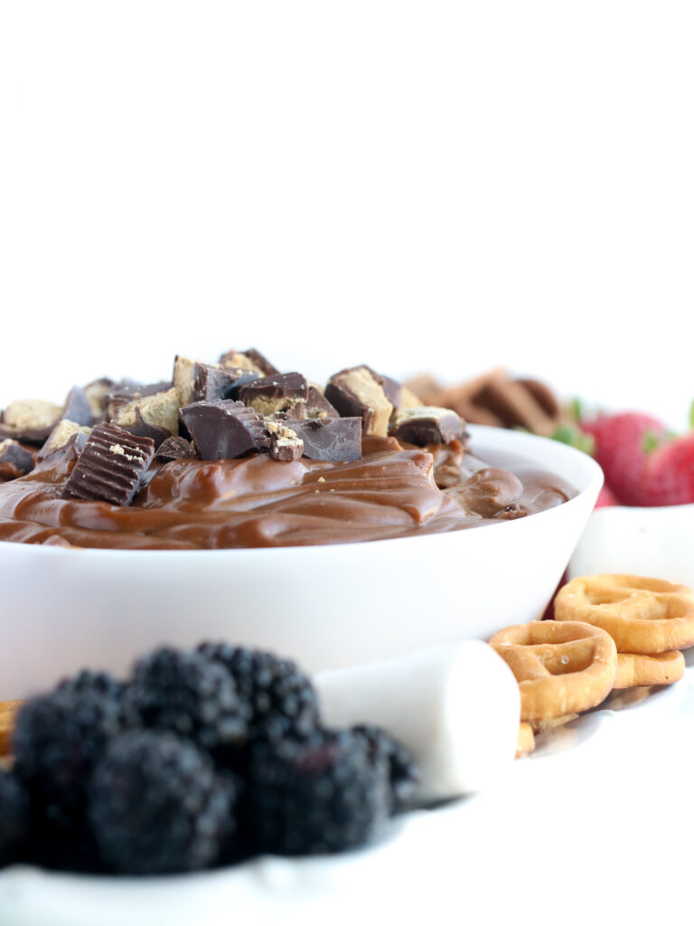 The best fruit dip surrounded by fresh fruit and pretzels